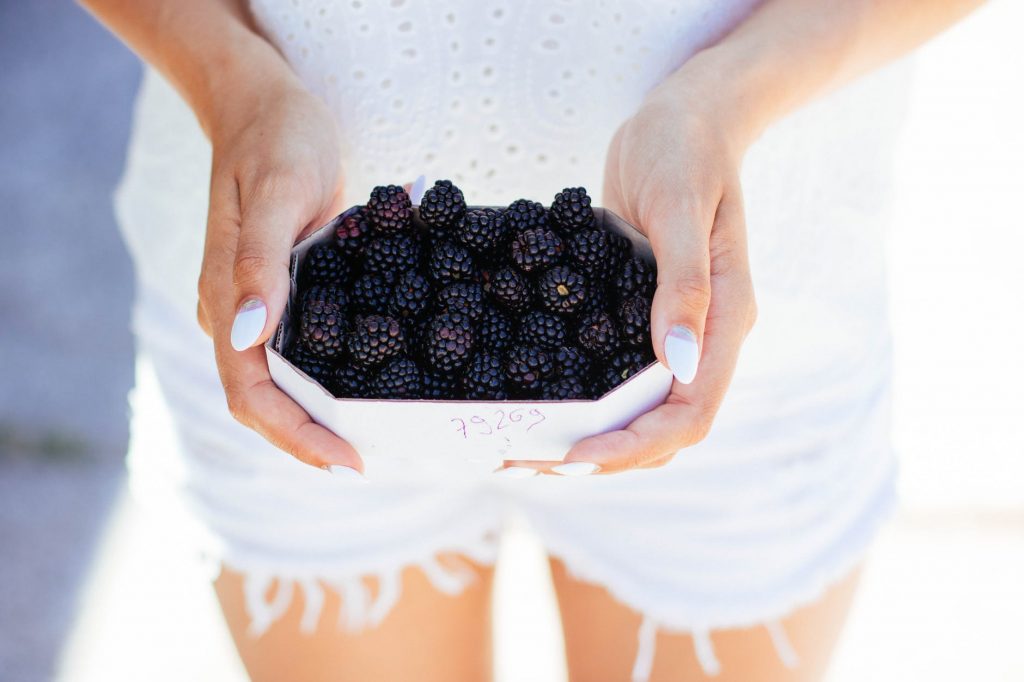 woman holding bowl of raspberries