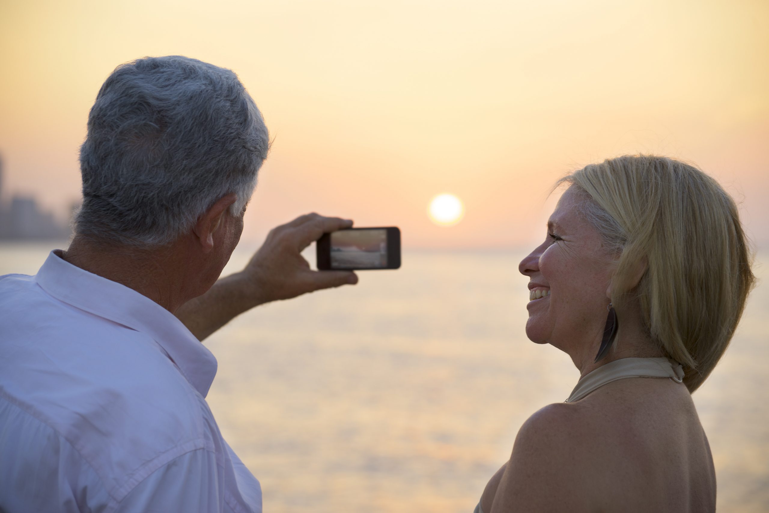 travel-and-active-elderly-man-and-woman-couple-of-tourists-looking-at-sea-and-taking-p-SBI-310153553-scaled-1